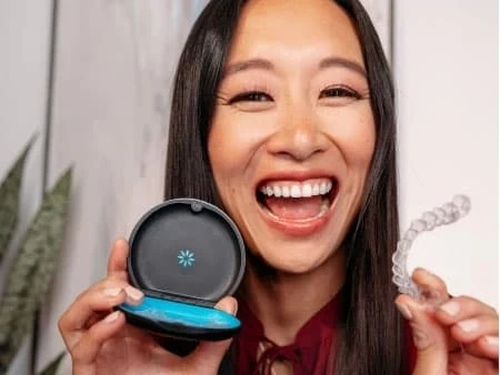 Smiling woman holding her Invisalign aligners and case